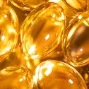 A macro photograph of shiny, golden-yellow, oval-shaped softgel capsules.