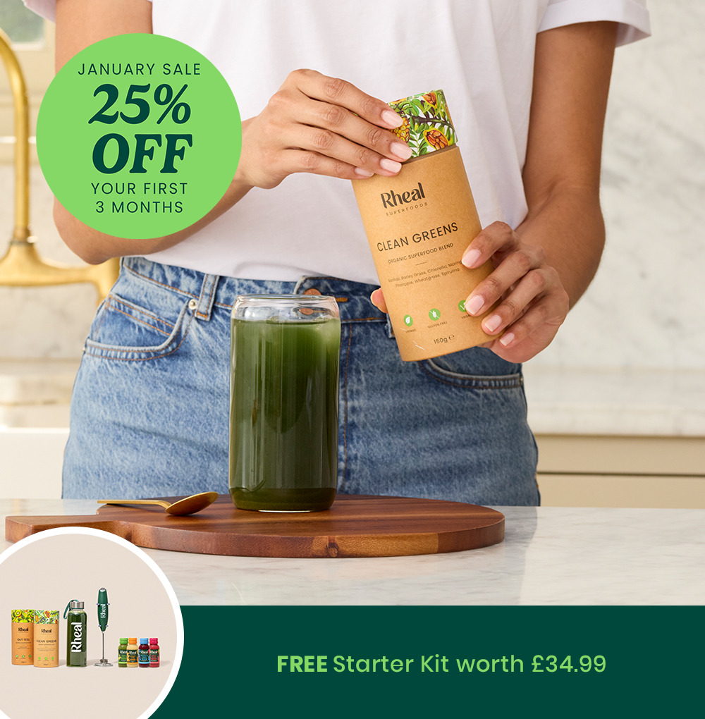 Person holding a superfood blend packet over a glass of green juice.