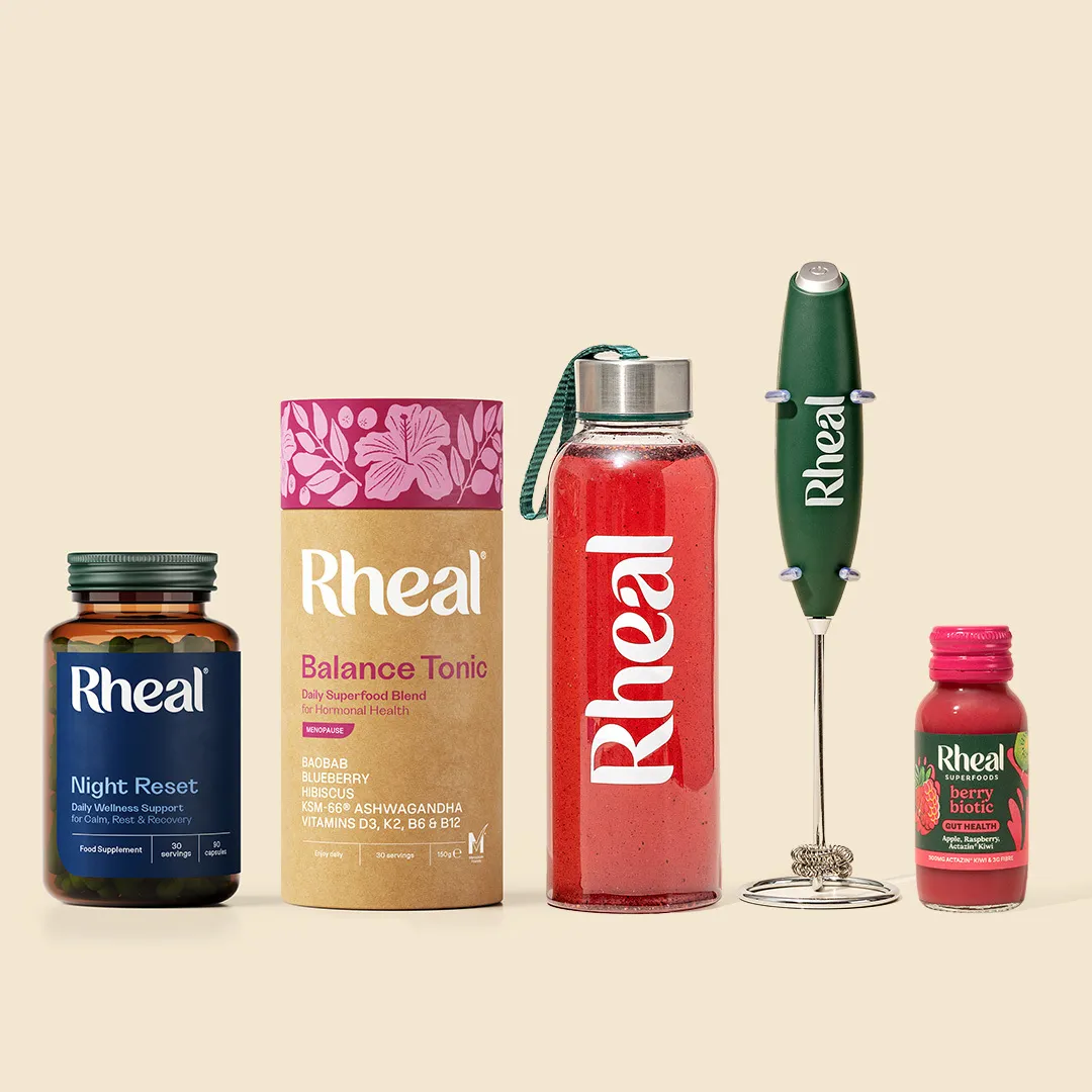 An assortment of Rheal brand health products, including supplements, a drink bottle, and a handheld electric frother.
