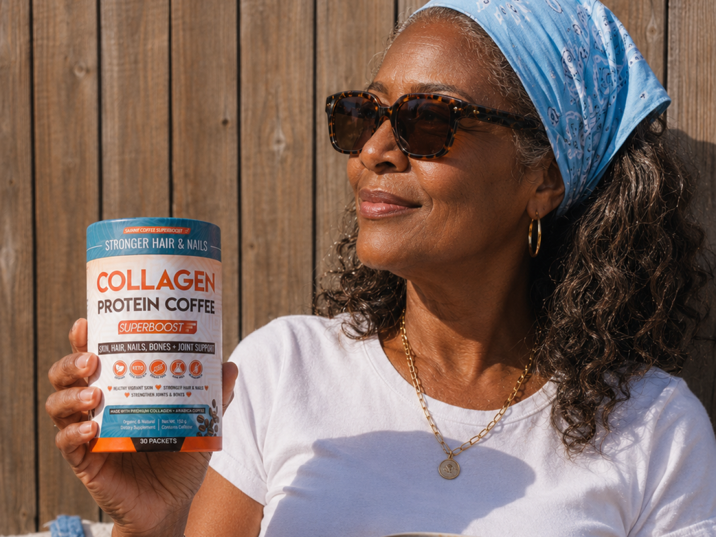 A smiling woman wearing sunglasses and a bandana holds a container of Collagen Protein Coffee outdoors.