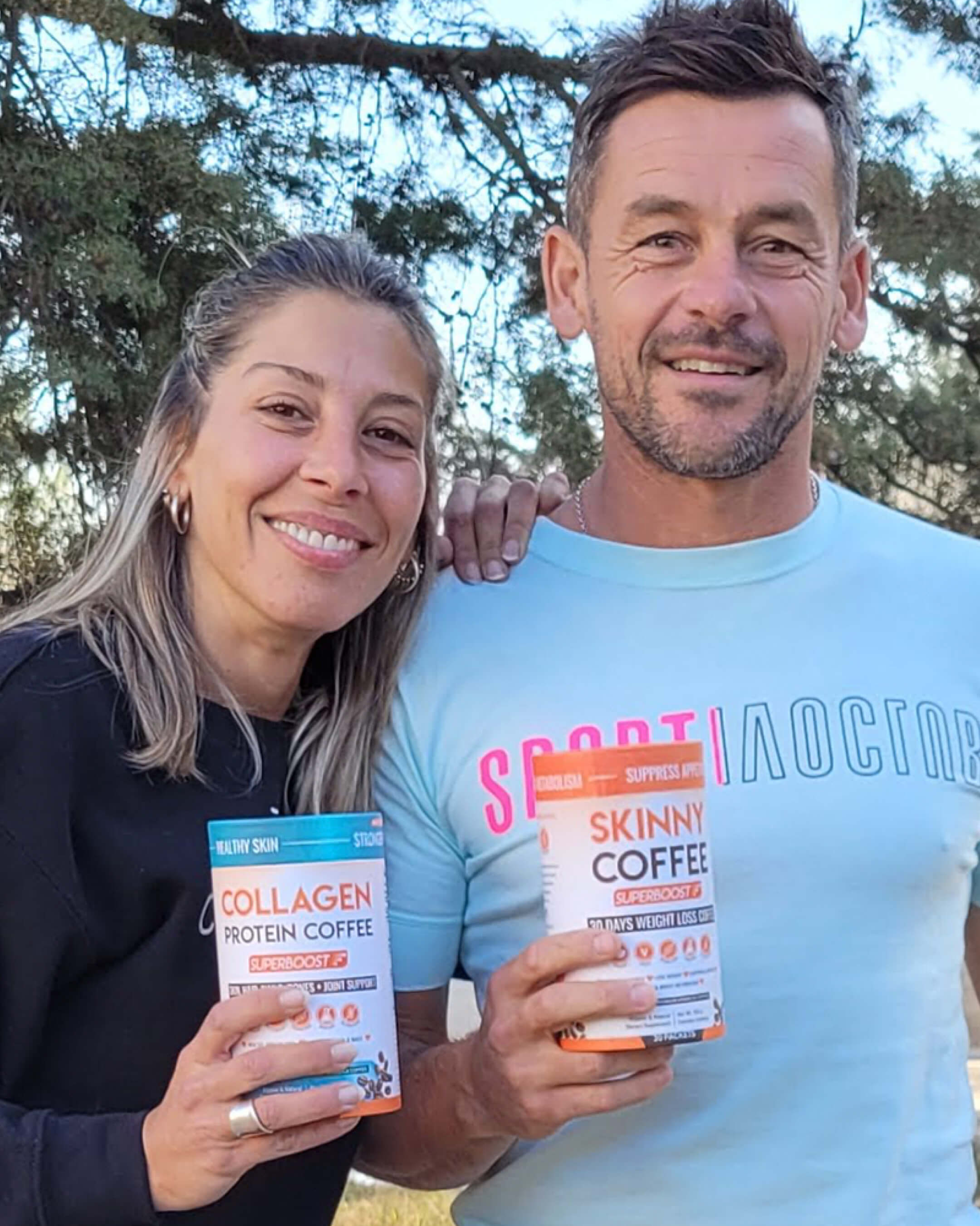 Two people smiling, holding collagen and skinny coffee products outdoors.