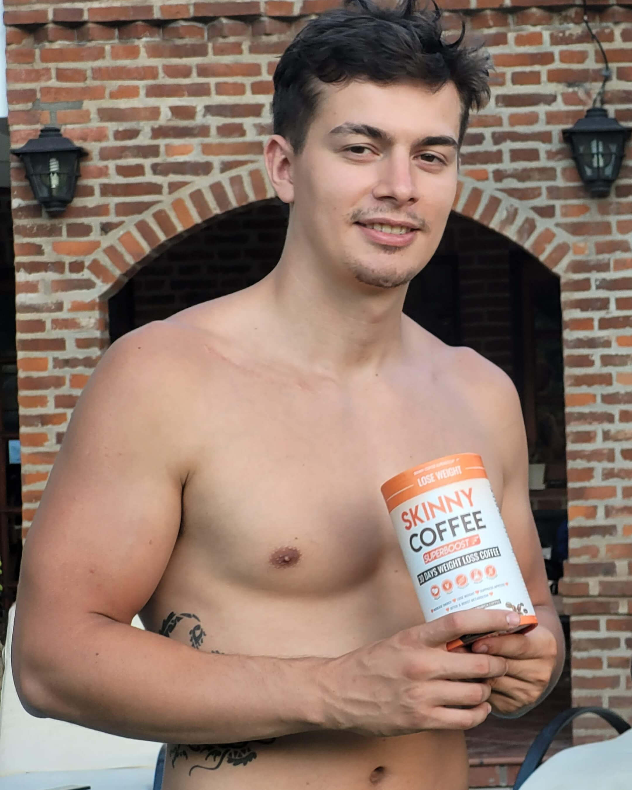 Shirtless man holding a Skinny Coffee product in front of a brick wall.