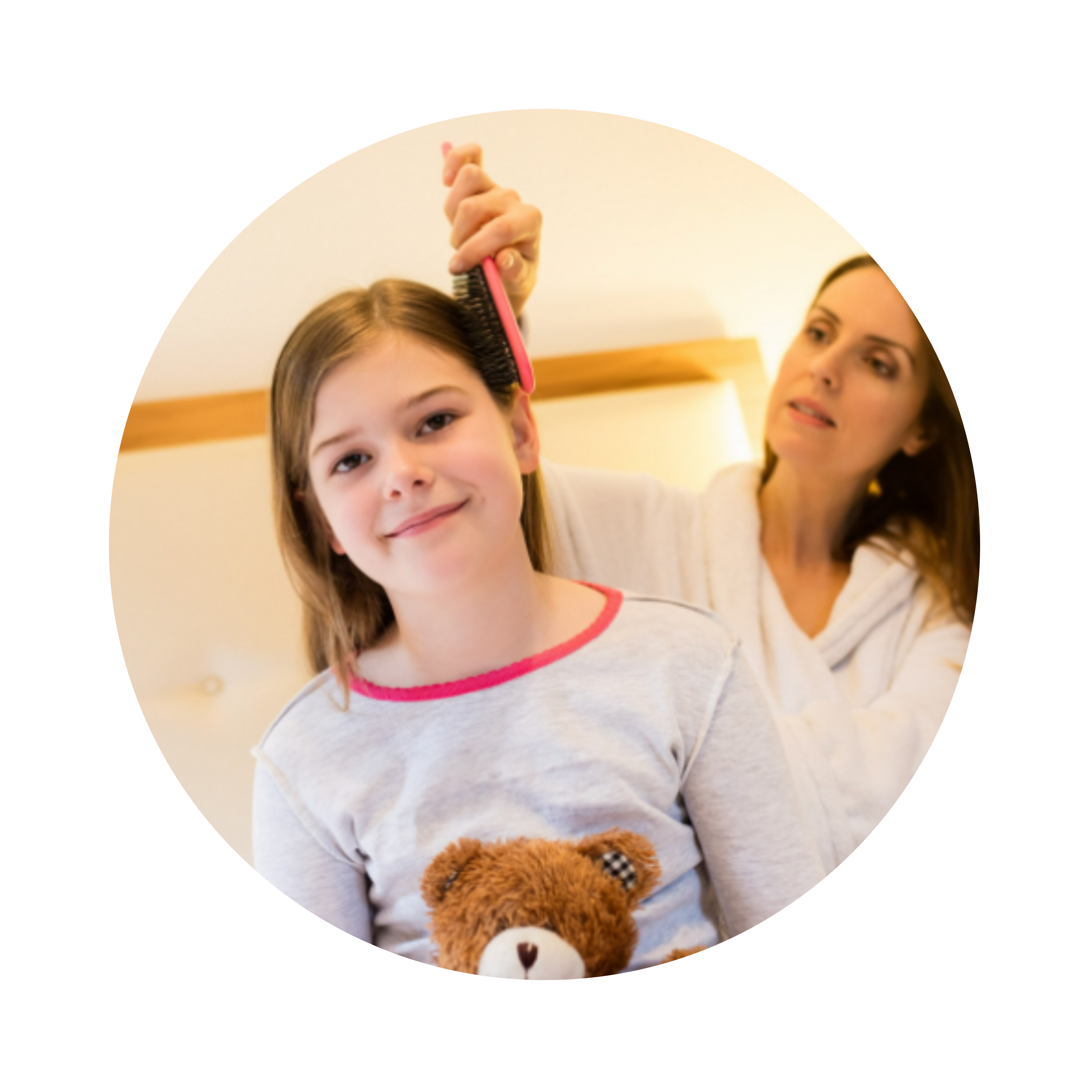 A woman brushes a young girl's hair while she holds a teddy bear.