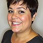 A headshot of a smiling woman with short dark hair.
