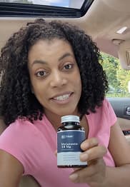 Person in a car holding a bottle of supplements.