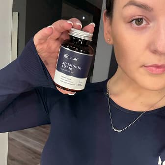 Person holding a bottle of melatonin supplement.