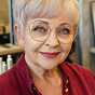 A woman with a short pixie haircut and large round glasses smiling at the camera.