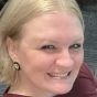 A close-up headshot of a smiling woman with blonde hair looking towards the camera.