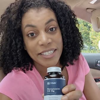 Person holding a bottle of melatonin in a car.