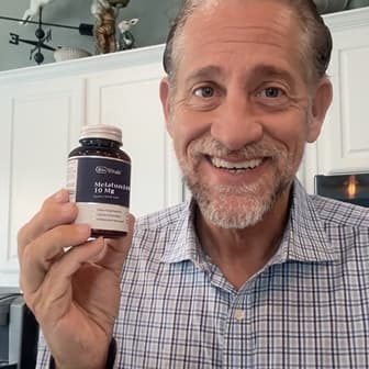 Person holding a bottle of melatonin in a kitchen.