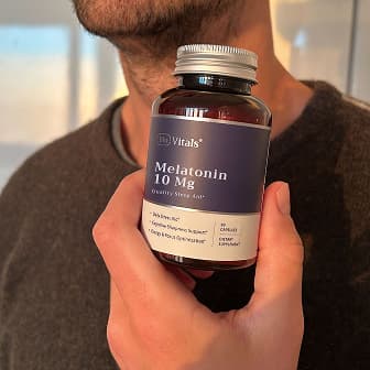 Person holding a bottle of melatonin supplement.