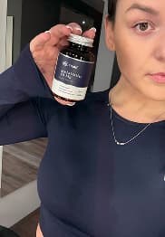 Person holding a bottle labeled 'Hyaluronic' in a room.