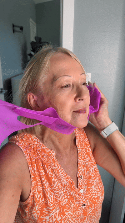 Person using a purple facial mask strap in a brightly lit room.