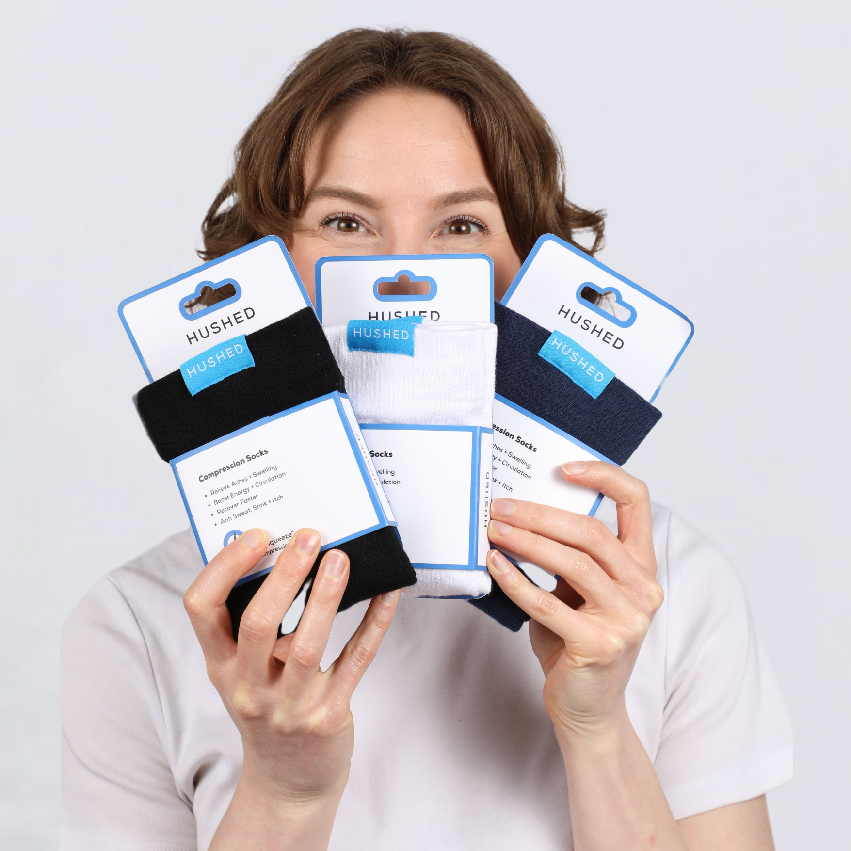 Person holding three pairs of Hushed compression socks in different colors.
