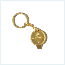 A gold-colored keychain with a circular medallion featuring a trident logo, shown on a white background.