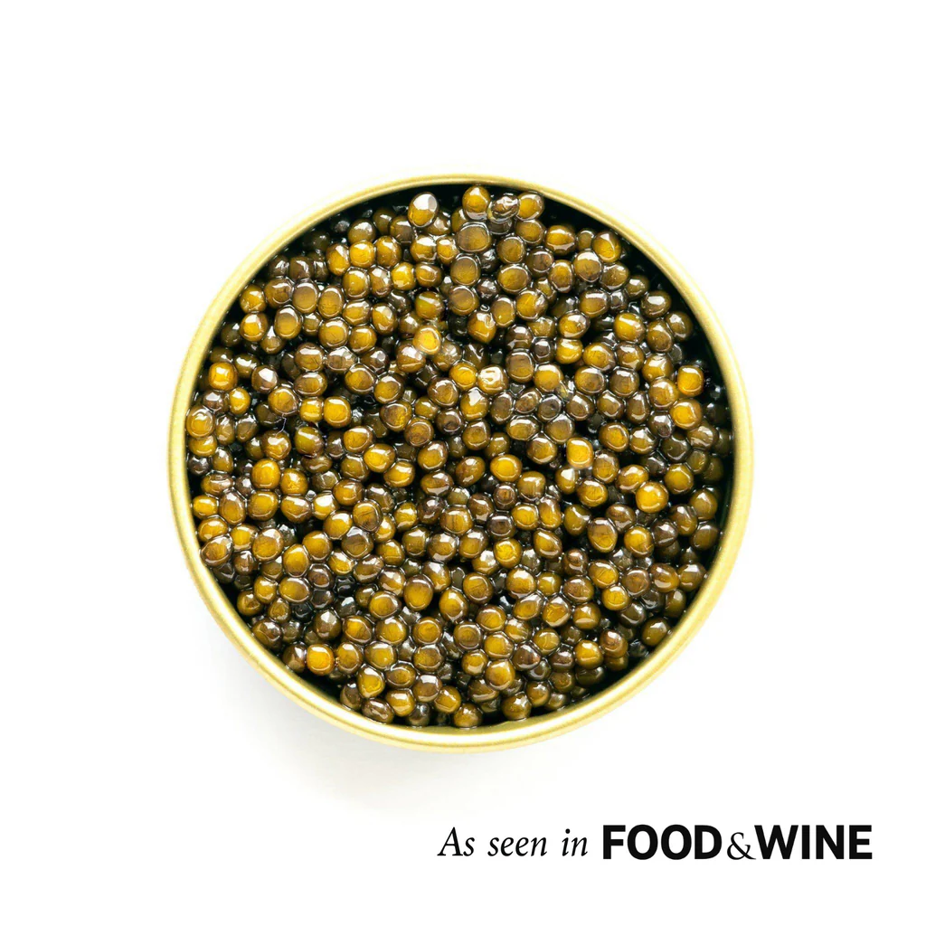 An overhead, close-up shot of an open tin of golden-brown caviar on a white background.