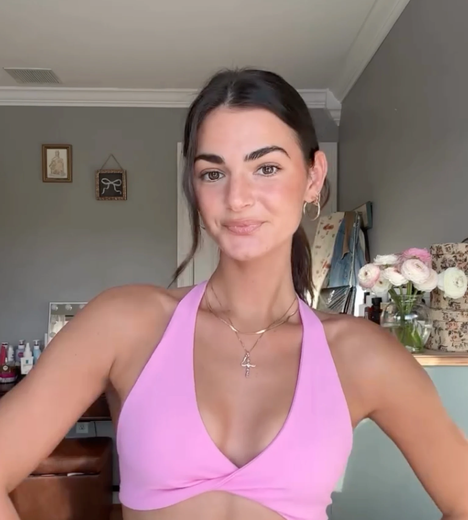 Woman in a pink halter top smiling indoors.