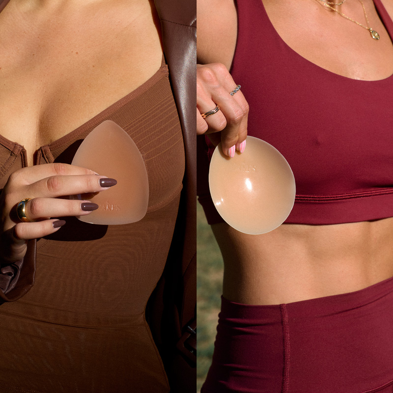 Two women holding silicone bra inserts against clothing.
