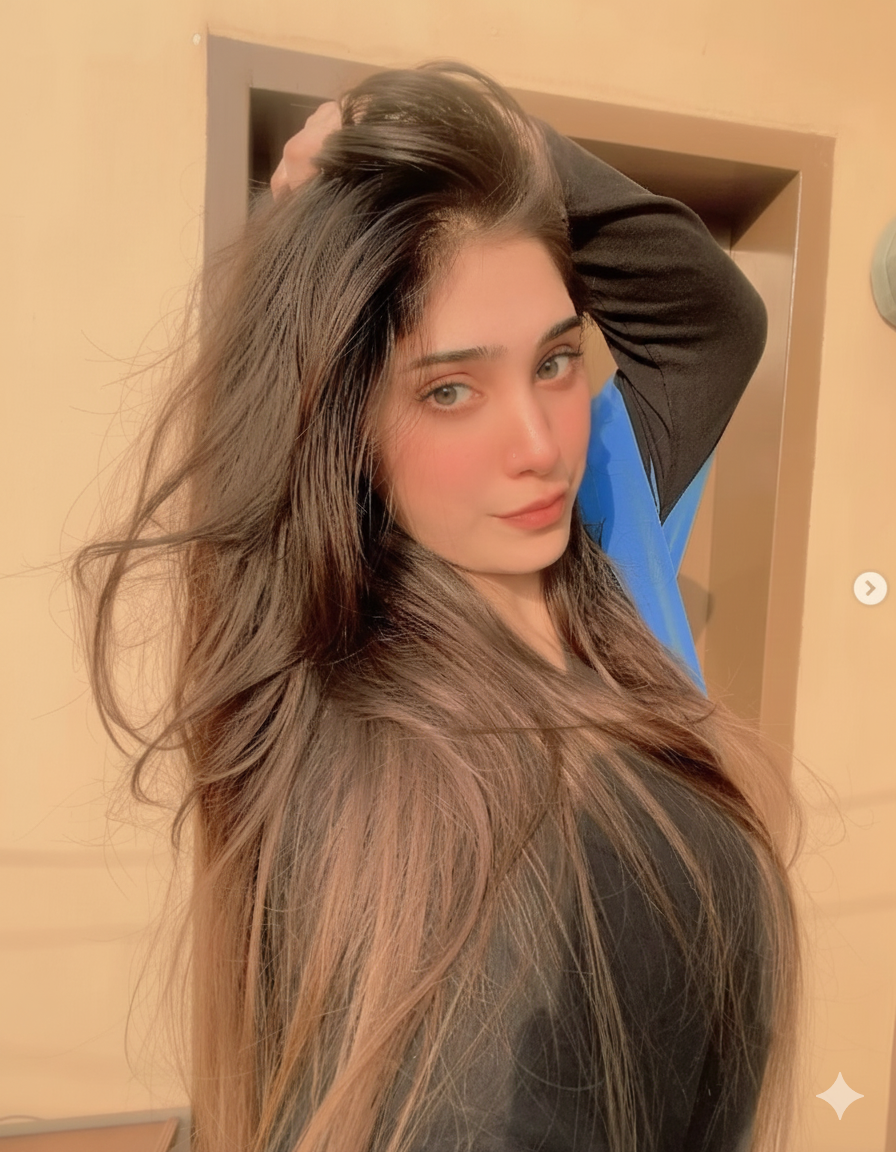 Person posing with long hair in sunlight, wearing a black top.