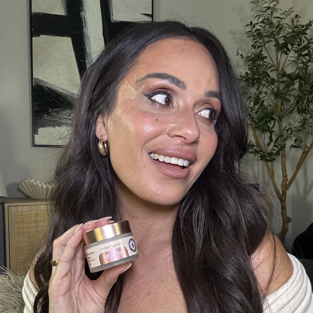 Person smiling holding a cosmetic product jar.