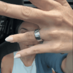 Hand with silver ring extended towards the camera, person blurred in background.