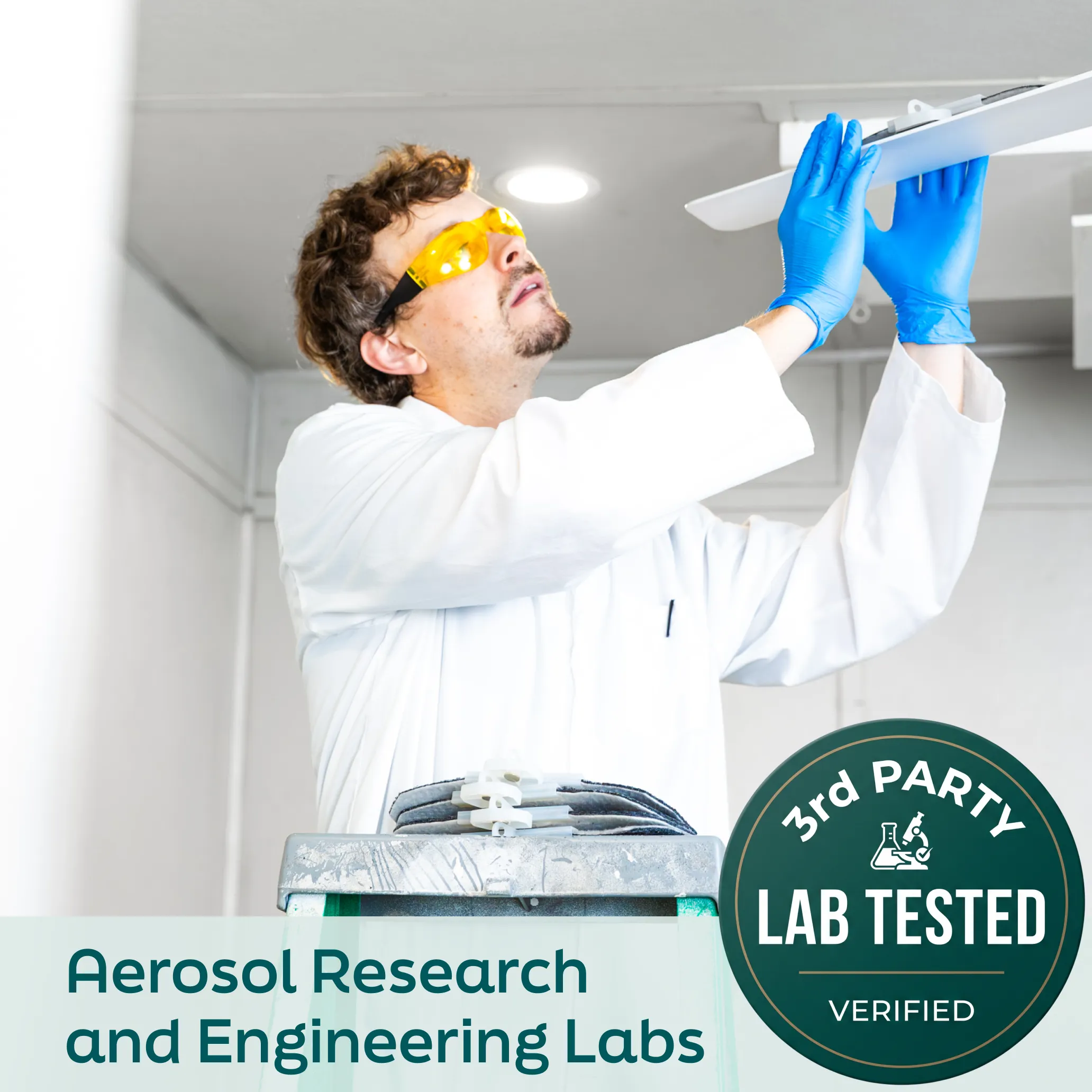 A man in a lab coat, safety goggles, and blue gloves adjusts a panel on the ceiling.