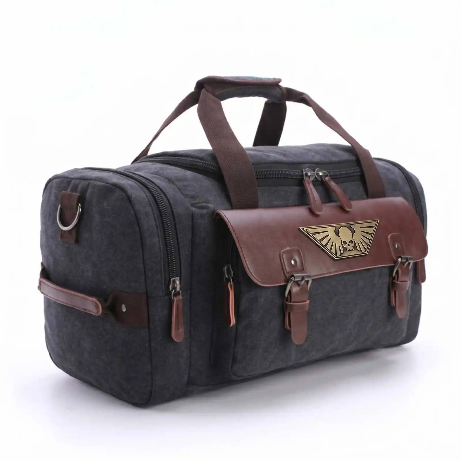 A dark gray canvas duffel bag with brown leather accents and a gold winged skull emblem.