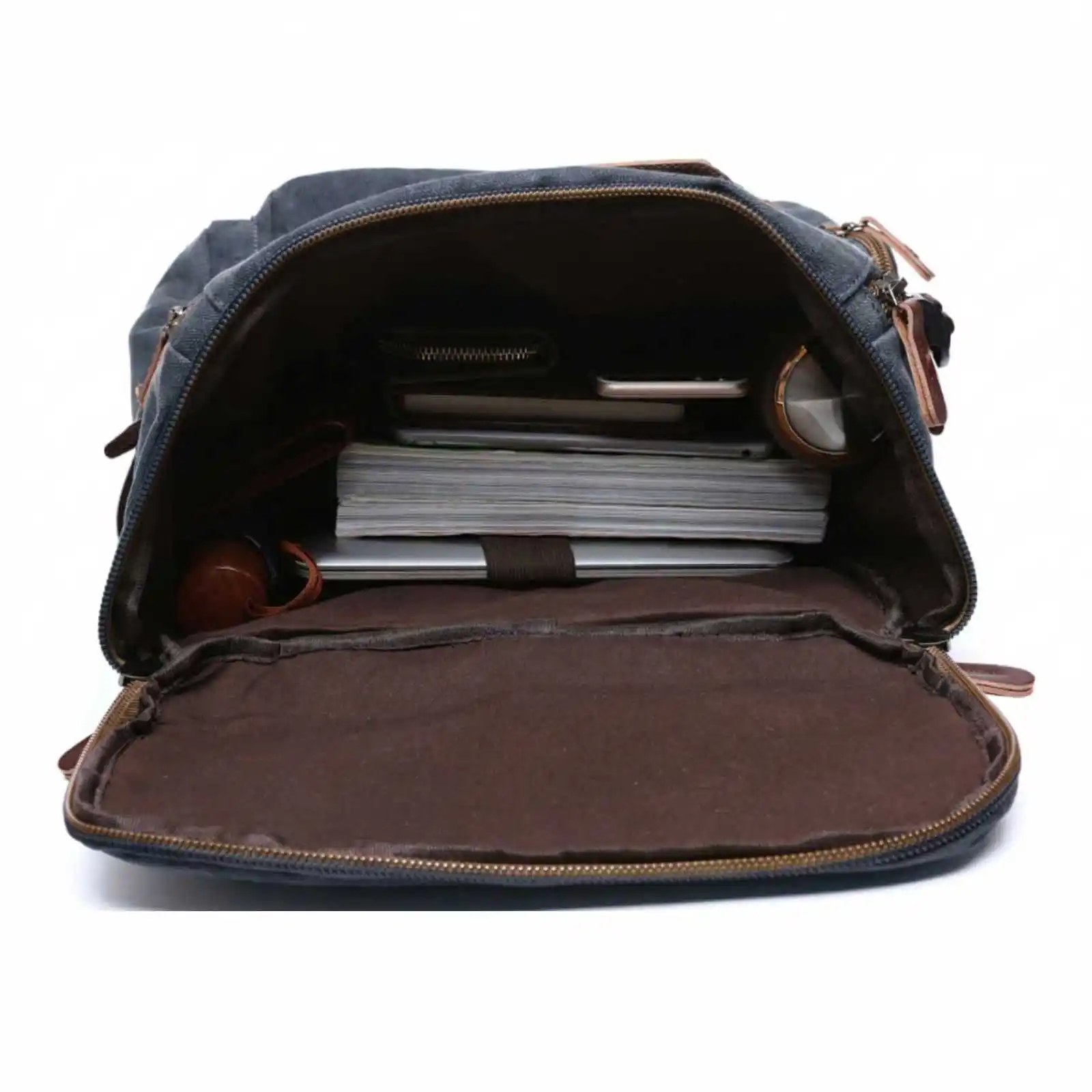 The interior of an open blue canvas backpack filled with books, a laptop, and other personal items.