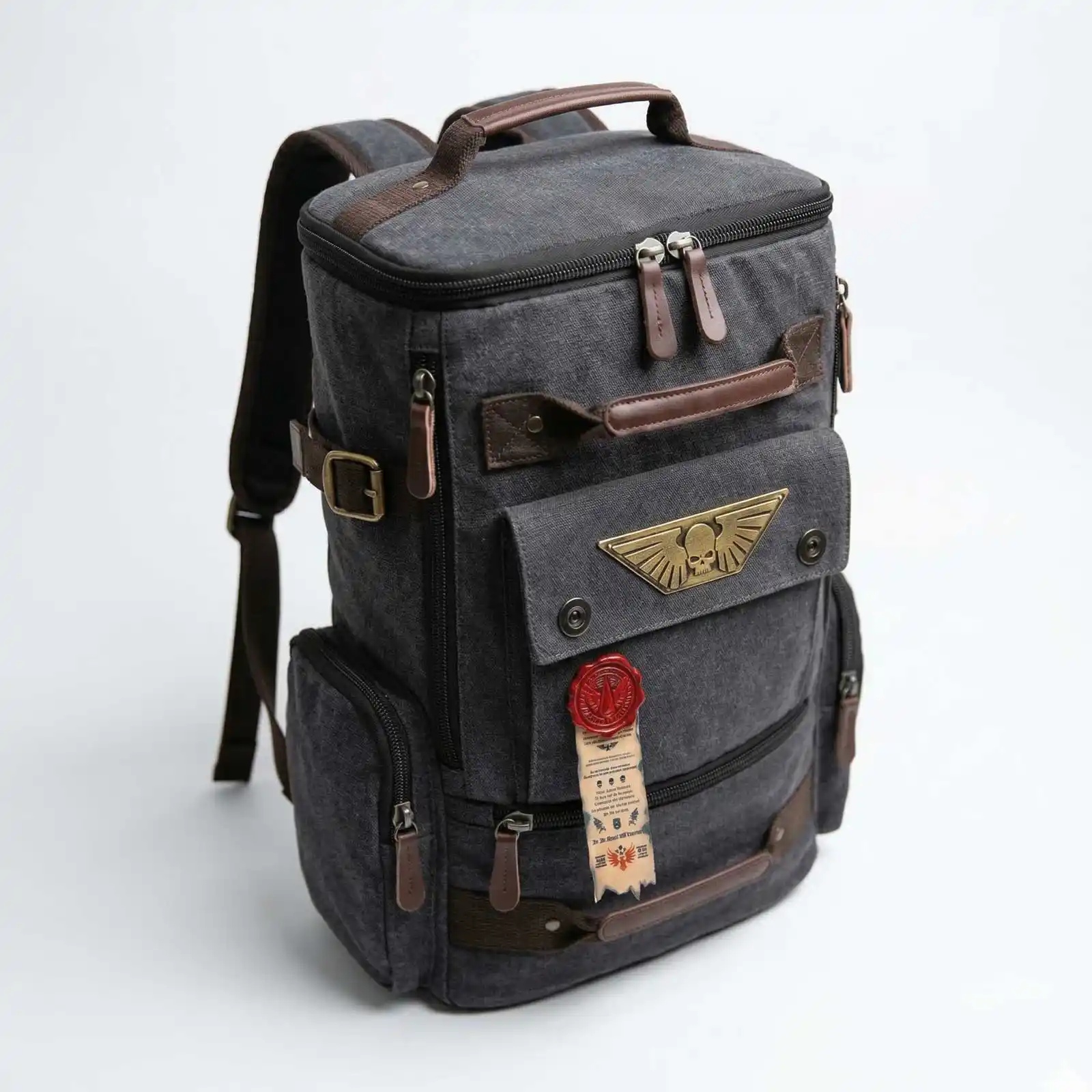 A gray canvas backpack with brown leather accents and a brass winged-skull emblem on the front pocket.