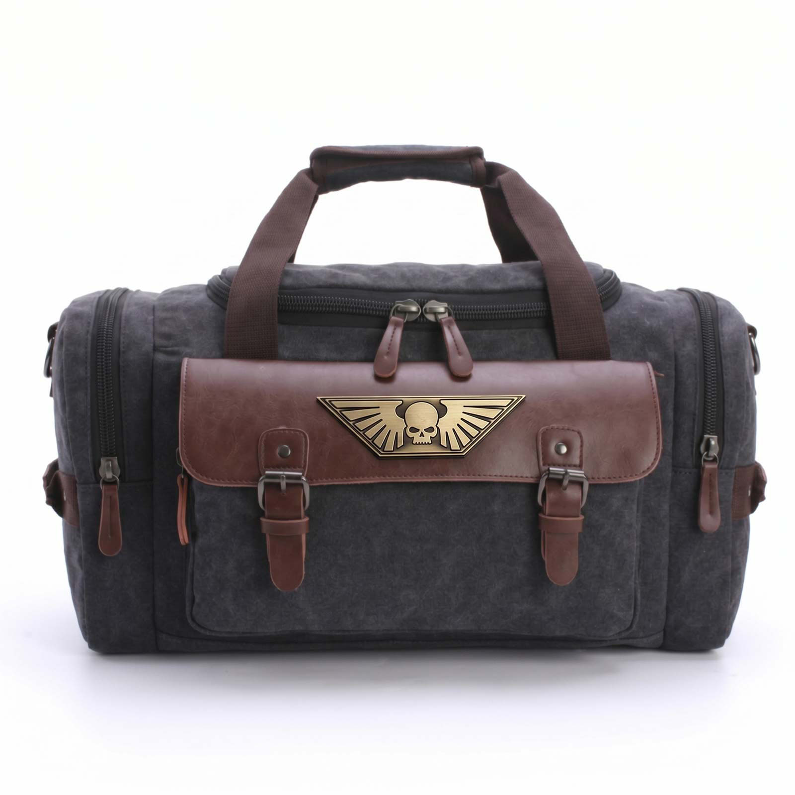 A grey canvas duffel bag with brown leather accents and a gold winged skull emblem on the front.