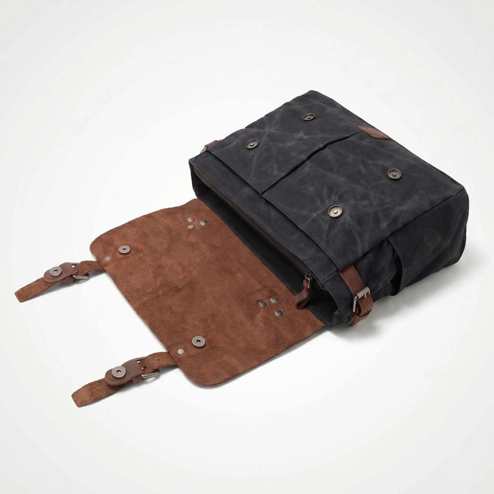 An open black canvas messenger bag with a brown suede flap against a white background.