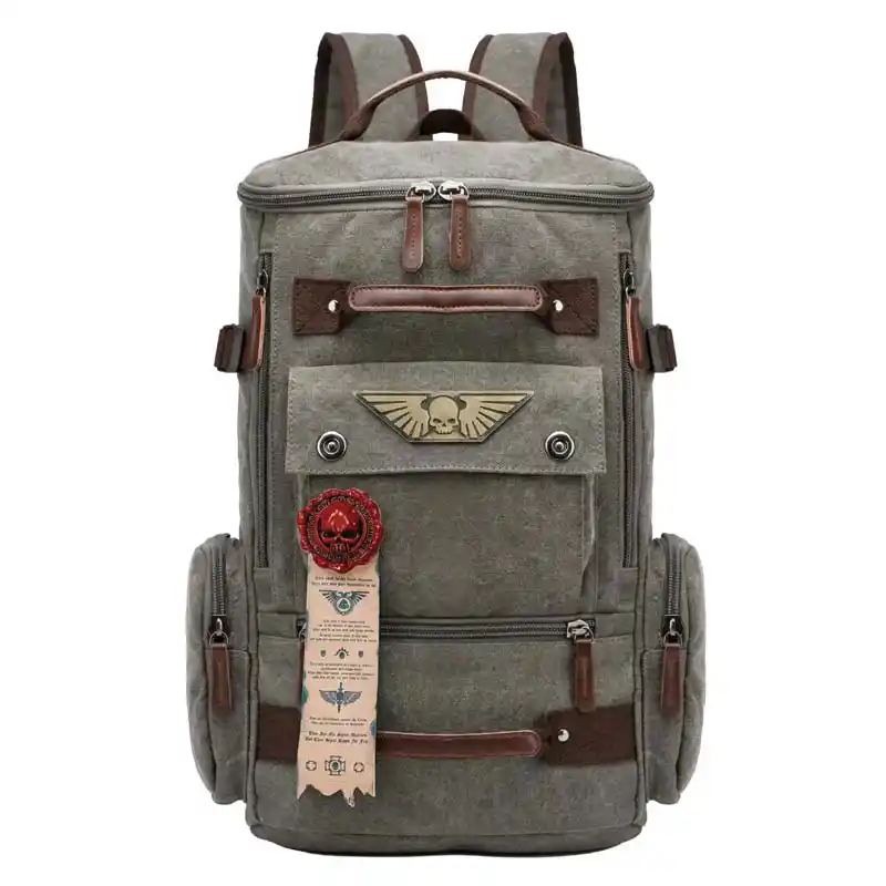 A grey canvas backpack with brown leather trim and a winged skull emblem on the front pocket.