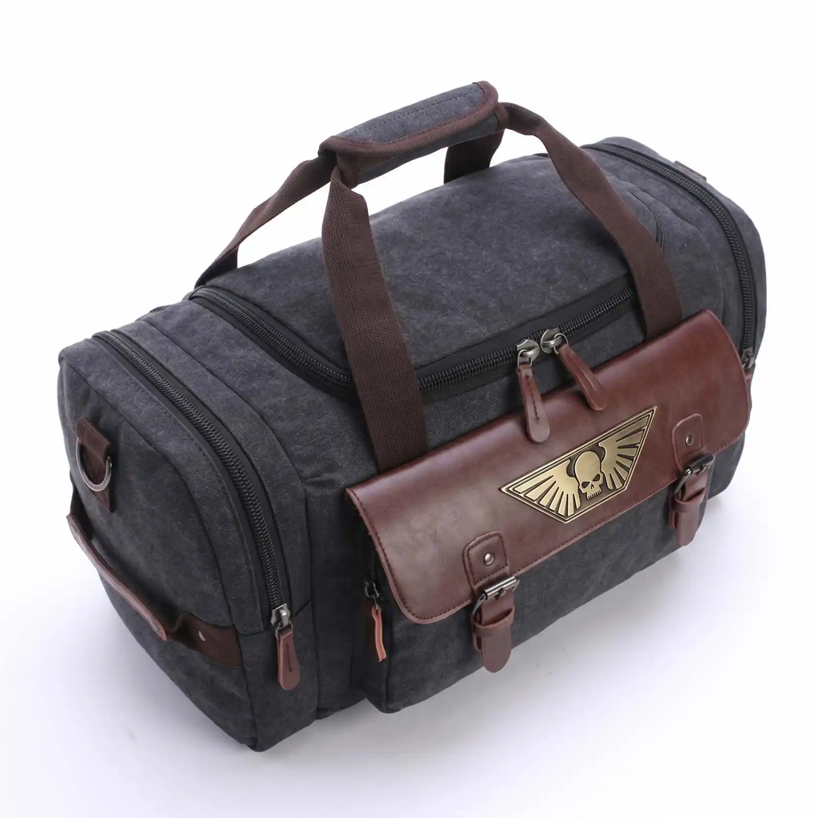 A dark gray canvas duffel bag with brown straps and a bronze winged skull emblem on the front pocket.