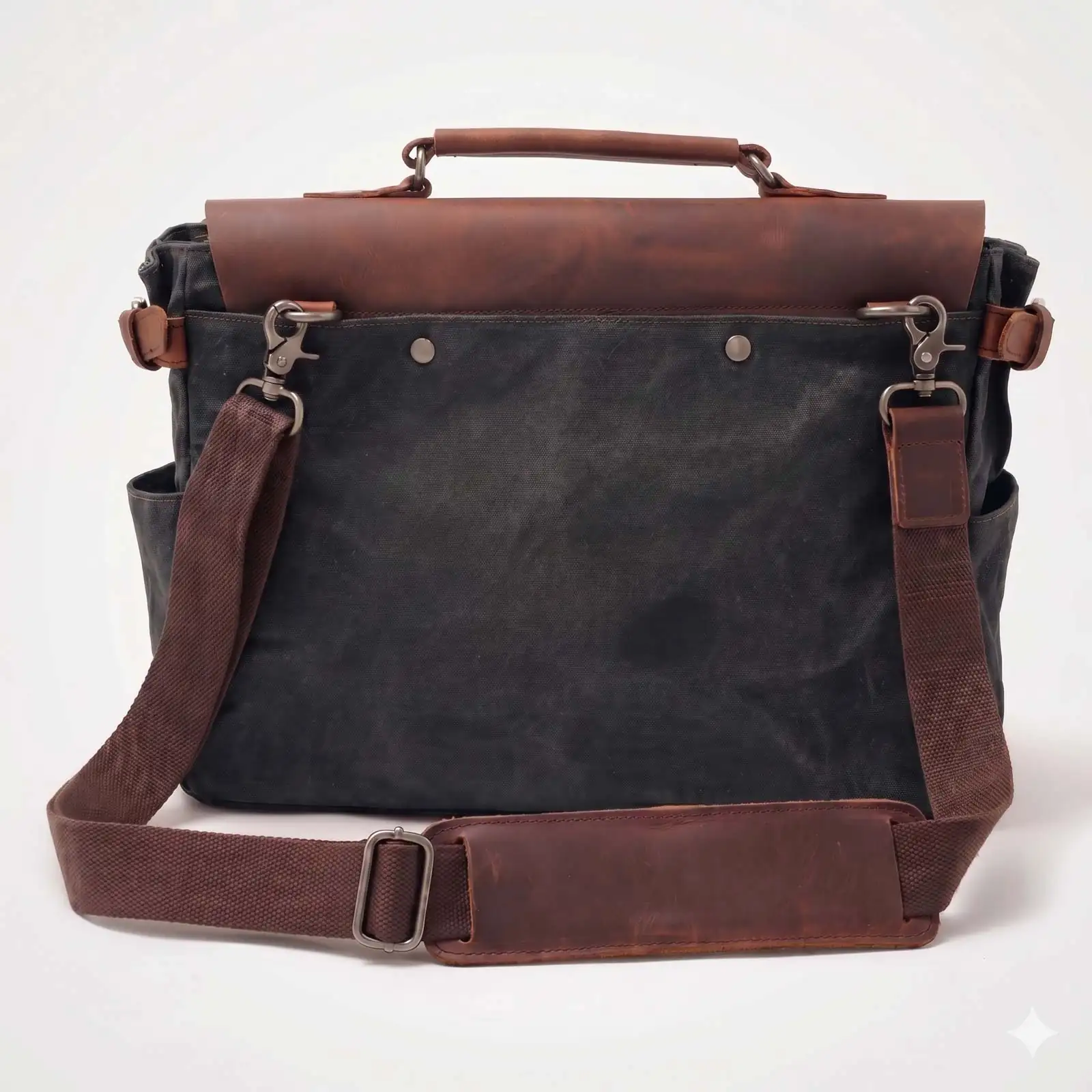 A black canvas messenger bag with brown leather flap, handle, and shoulder strap against a white background.