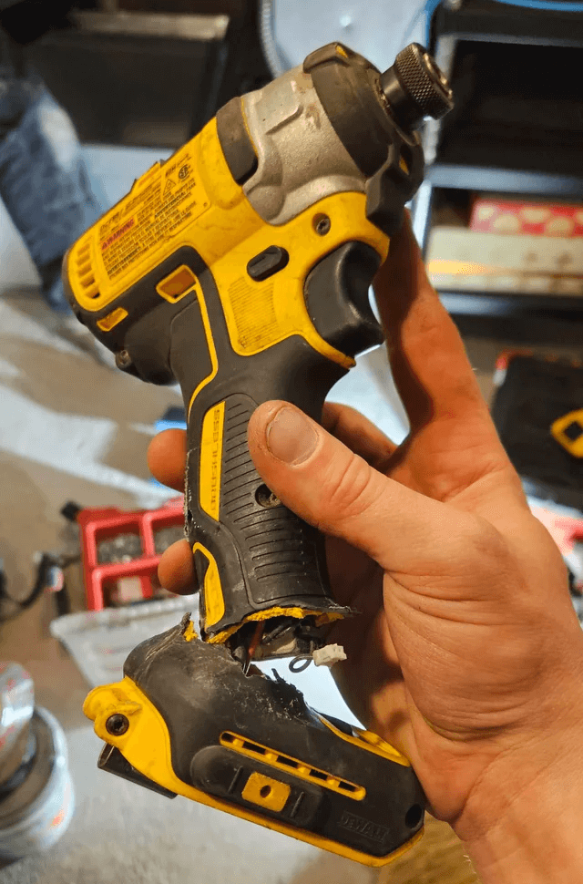 Person holding a broken yellow and black power drill.