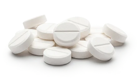 A small pile of round, white, scored tablets on a white background.
