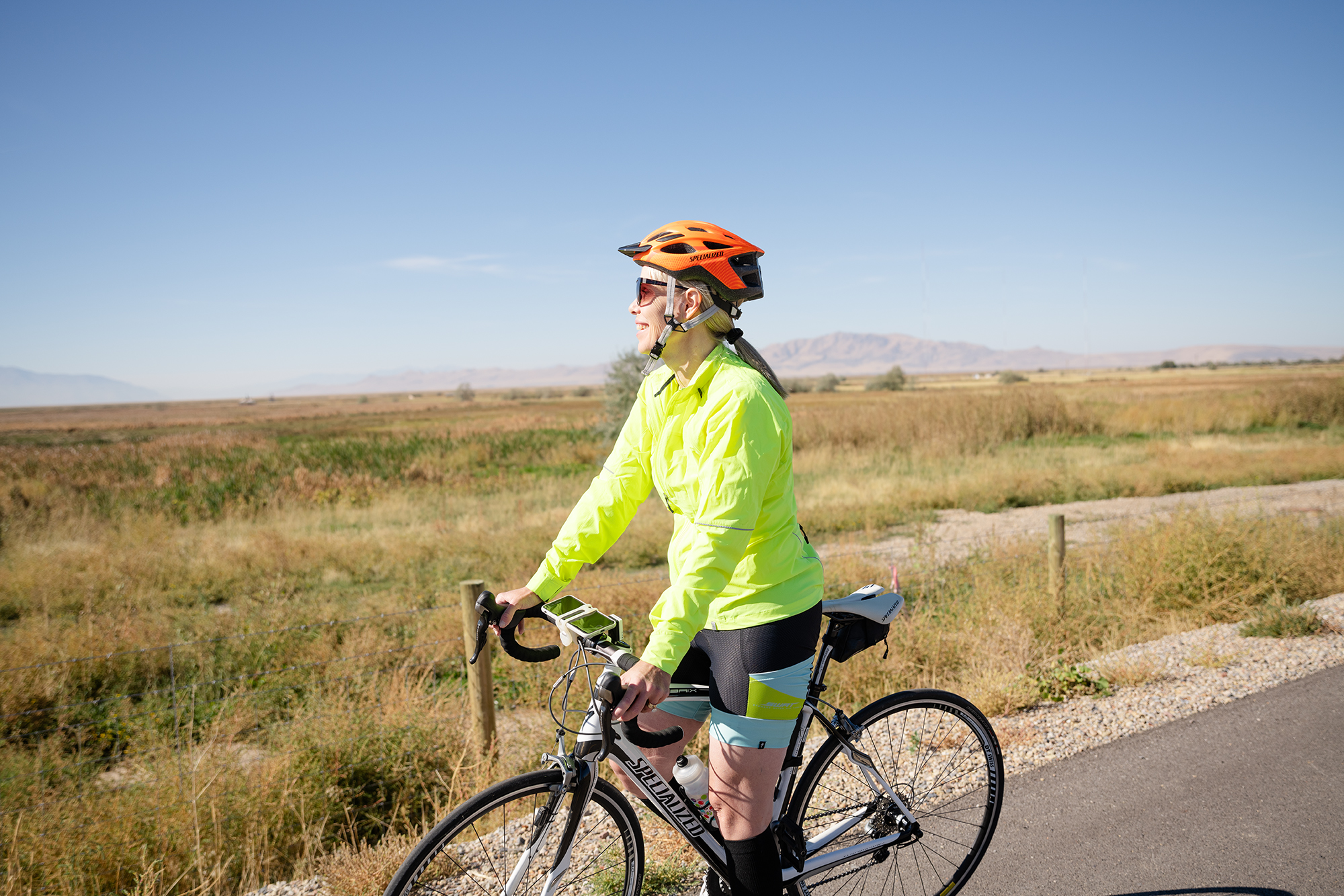 Person in bright jacket and helmet cycling on a rural path.