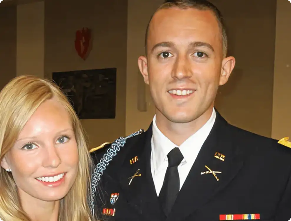 A man in a military uniform and a woman smiling, indoors.