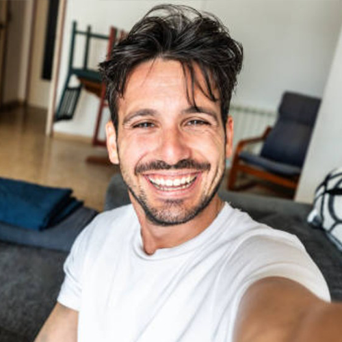 Smiling person taking a selfie in a living room.