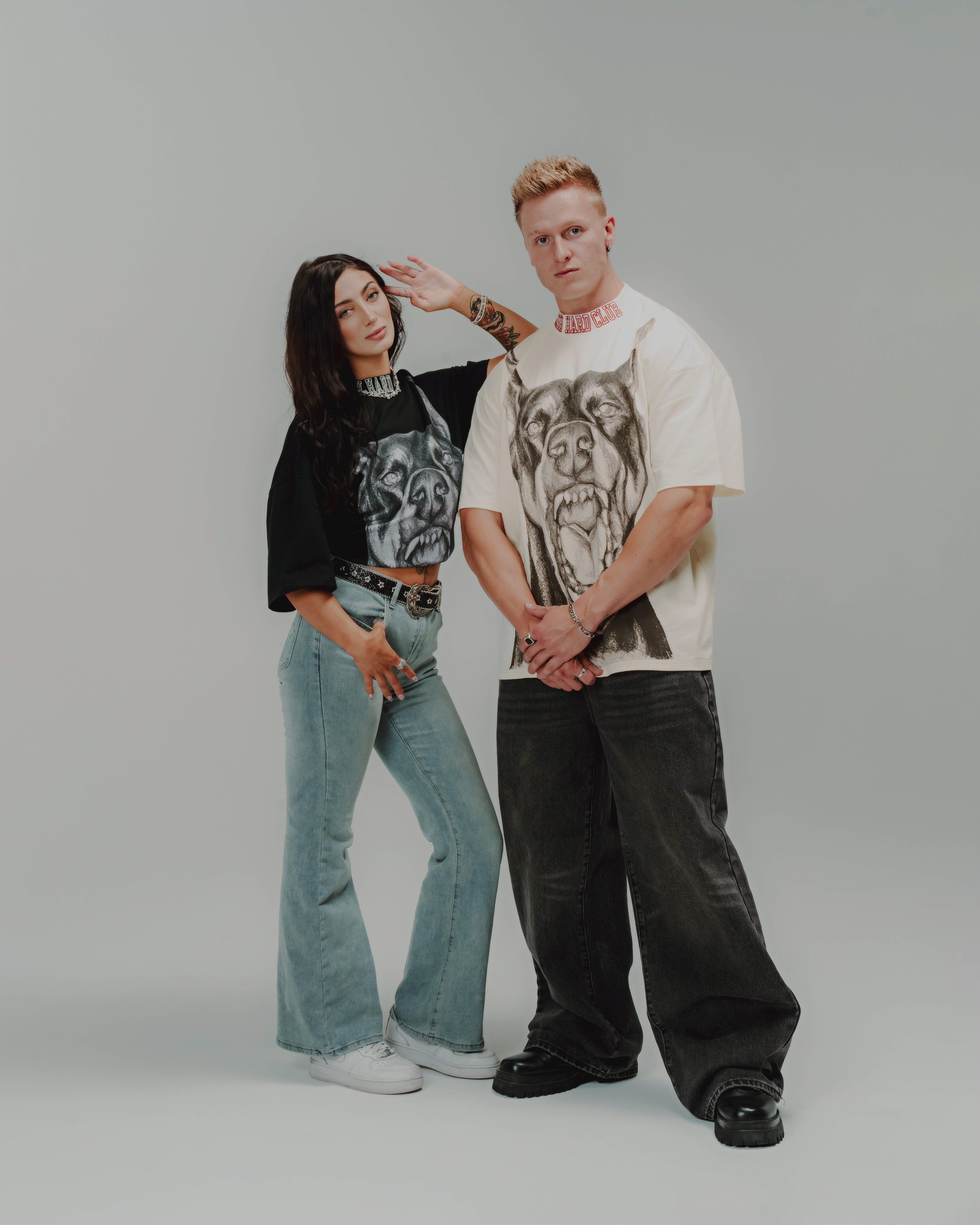Two people wearing graphic t-shirts with dog prints, posing against a plain background.