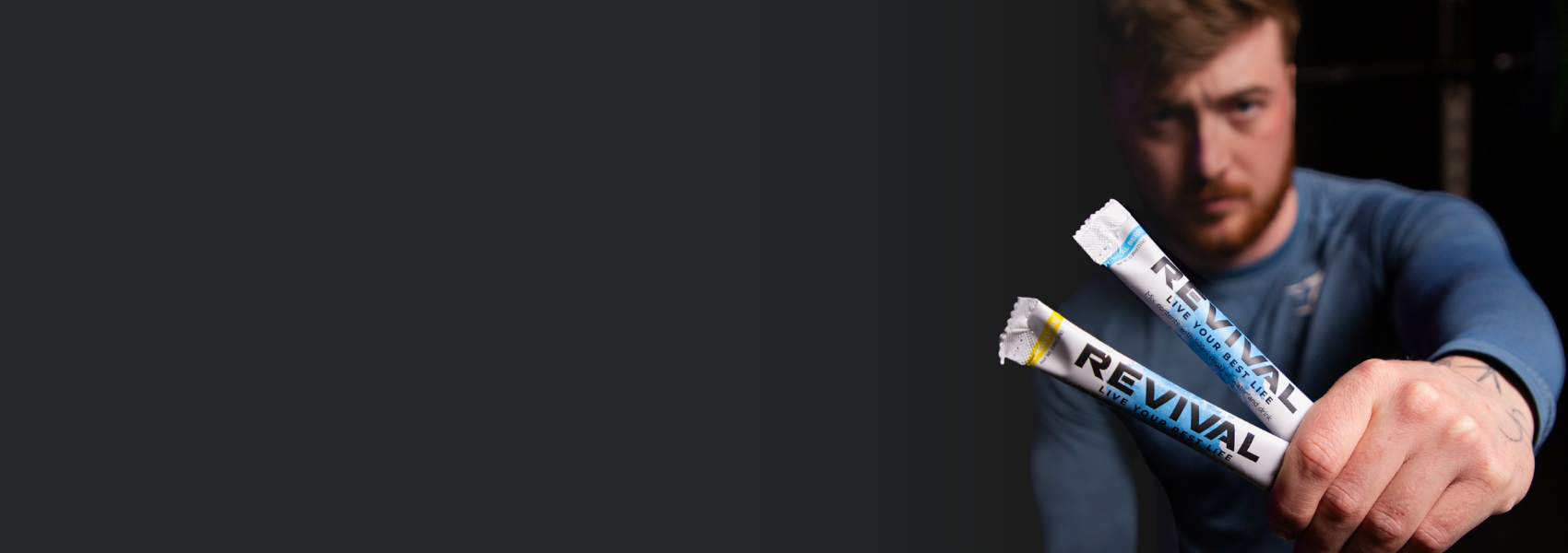 Man holding two Revival hydration sticks in his hand.