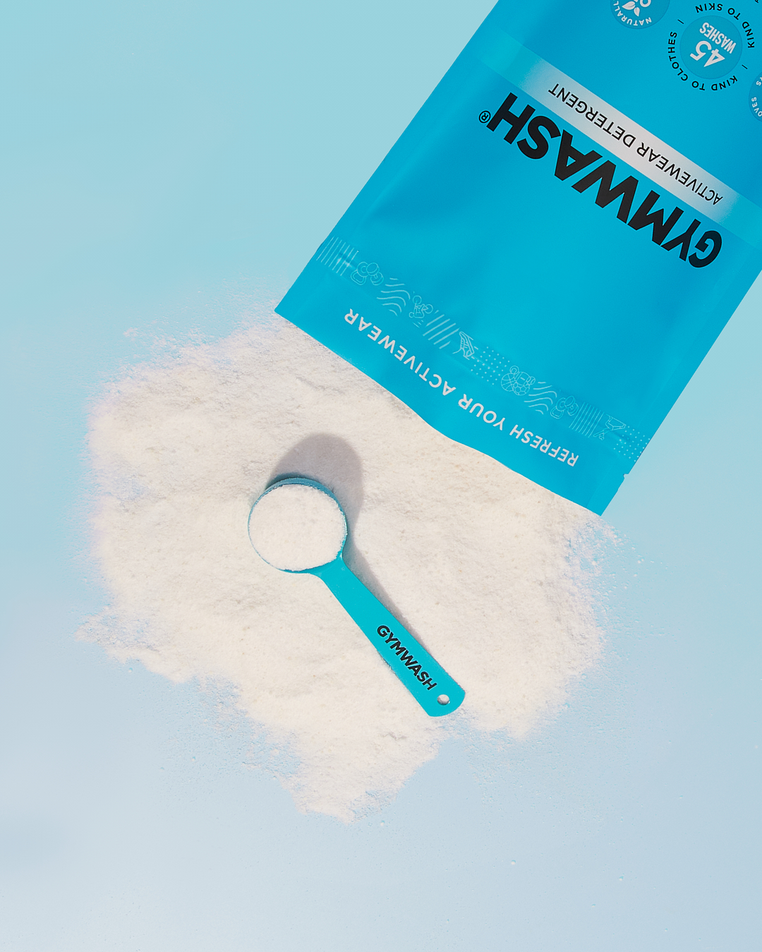 Blue bag of detergent with a scoop on a light blue background.