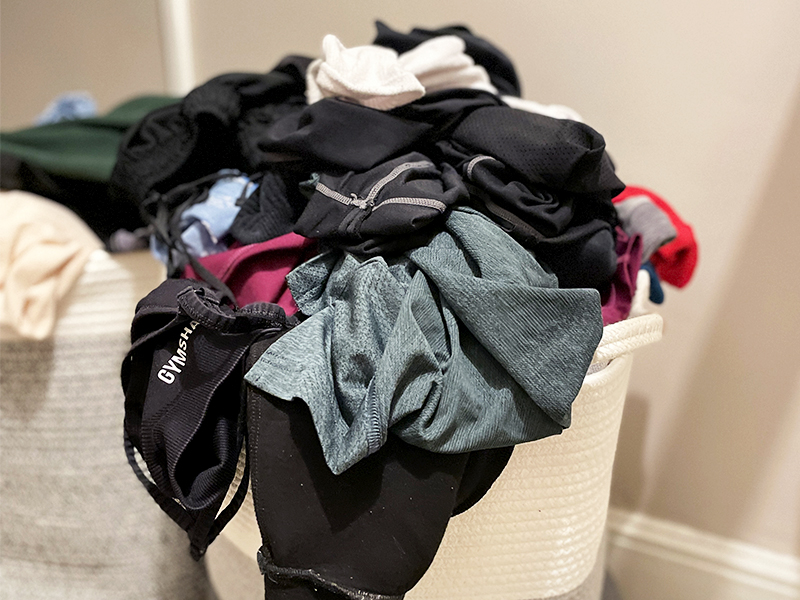 Laundry basket overflowing with mixed clothing items.