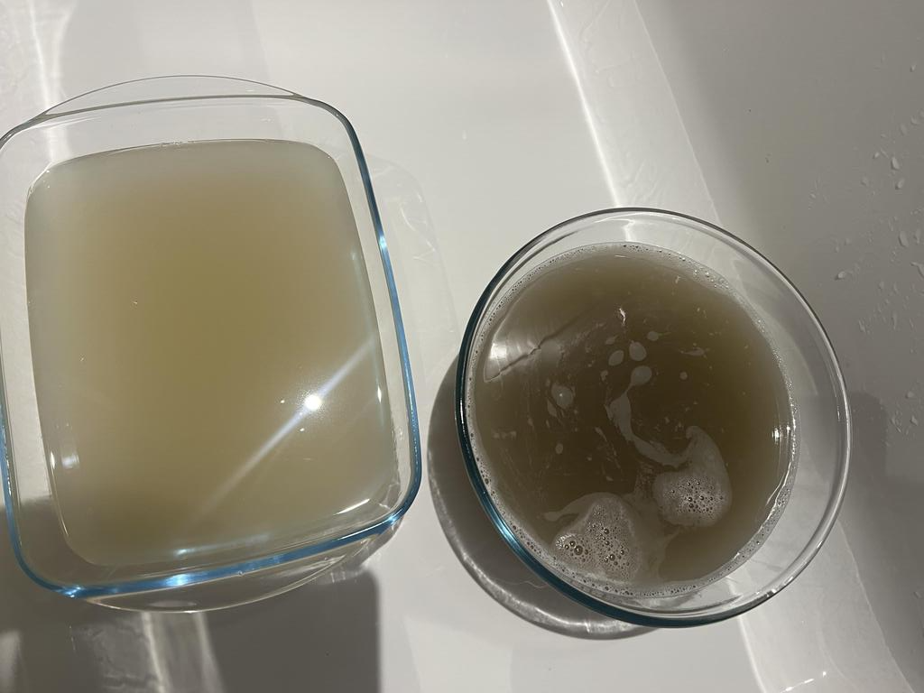 Two glass containers with cloudy liquid on a white surface.