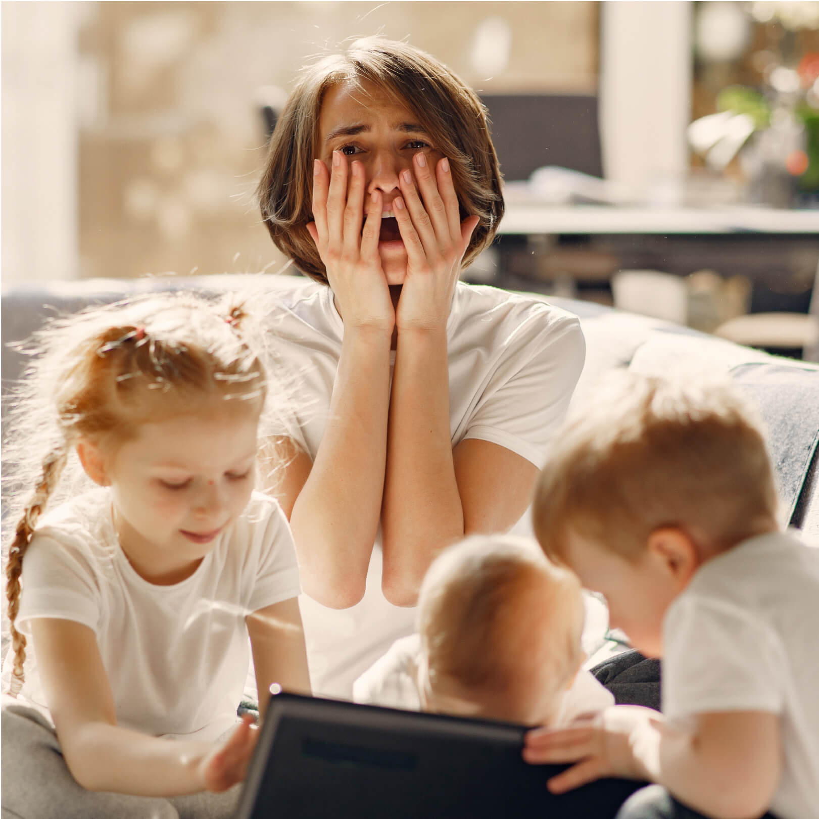 Woman looking overwhelmed with three children around her.