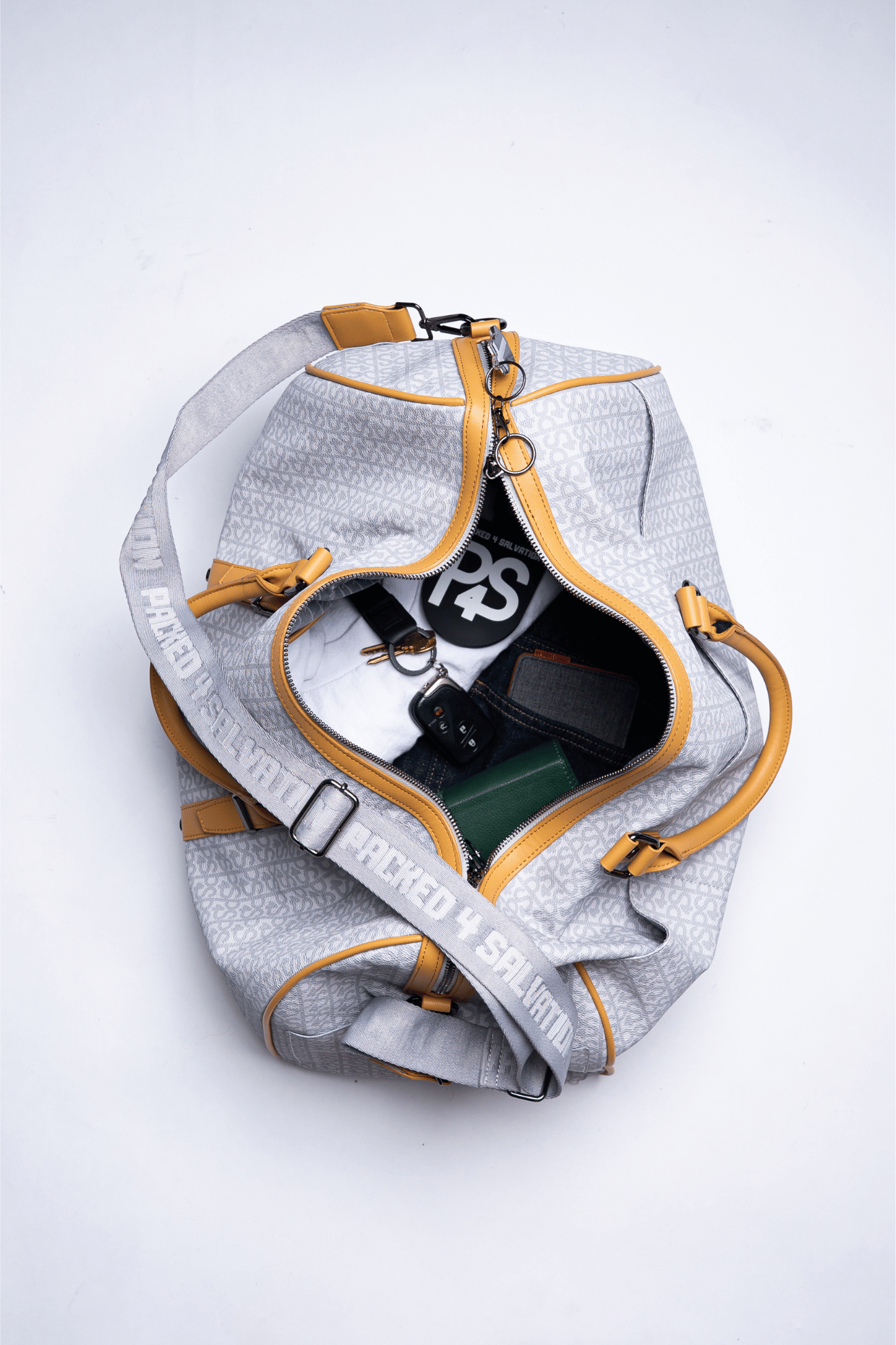 Open duffel bag with clothes, keys, and a book inside.