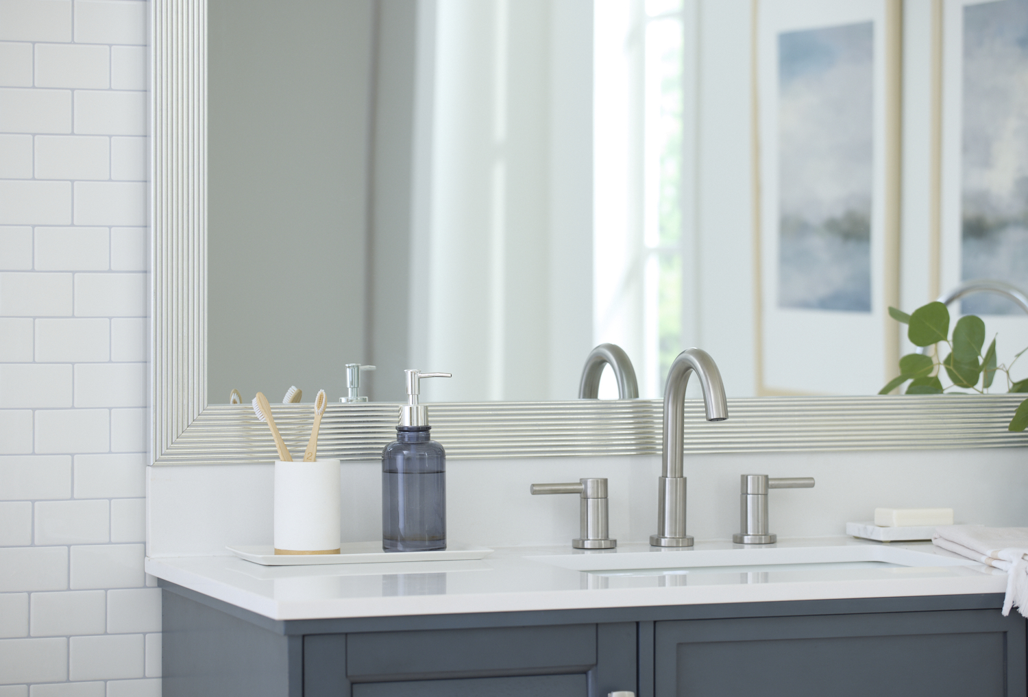 Bathroom sink with soap dispenser, toothbrush holder, and large mirror.