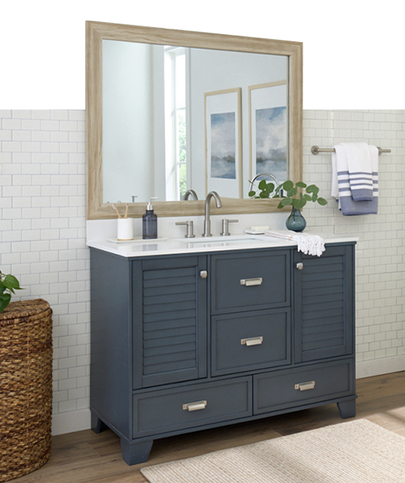 Bathroom vanity with a large mirror, blue cabinet, and decorative items.