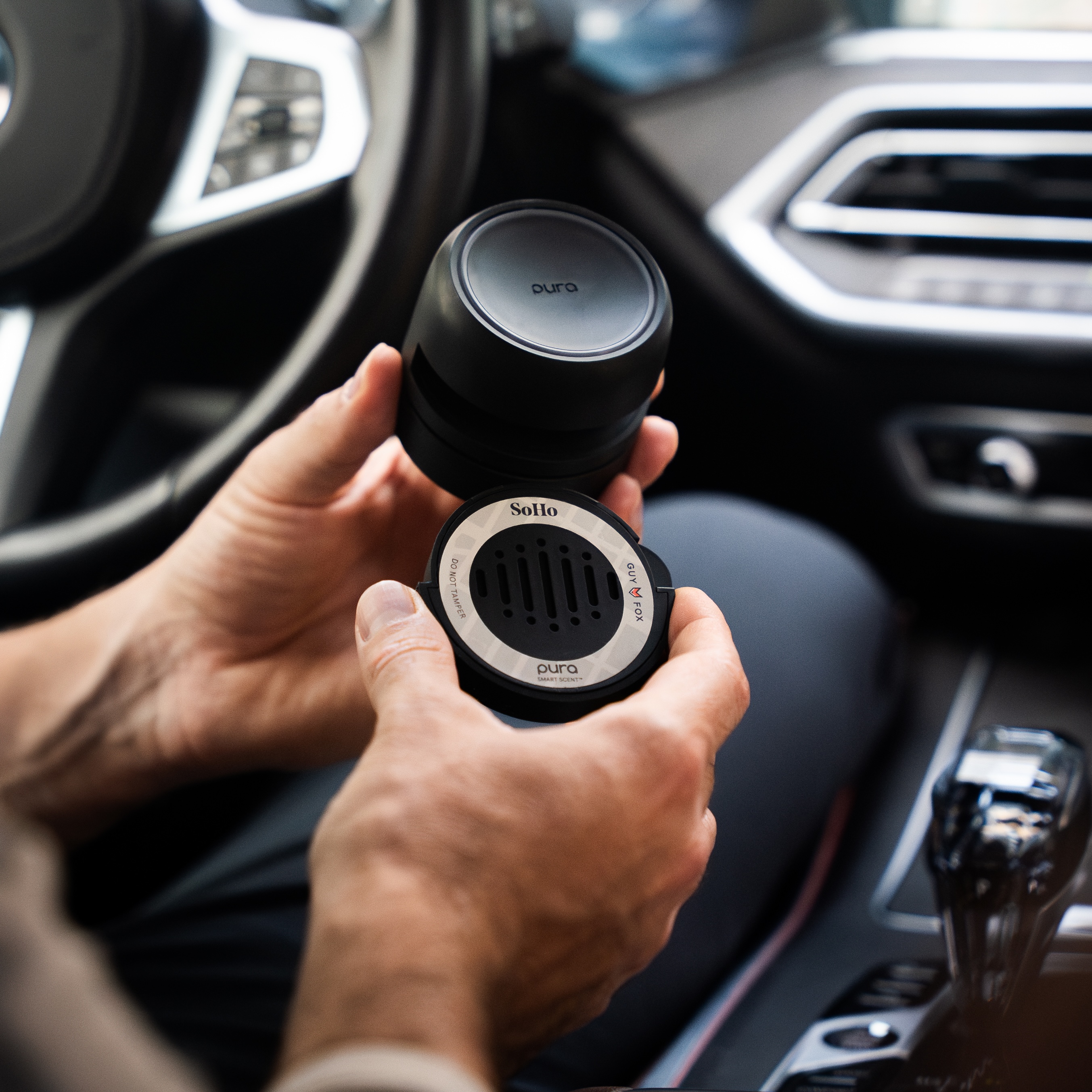 Person holding a car air freshener inside a vehicle.