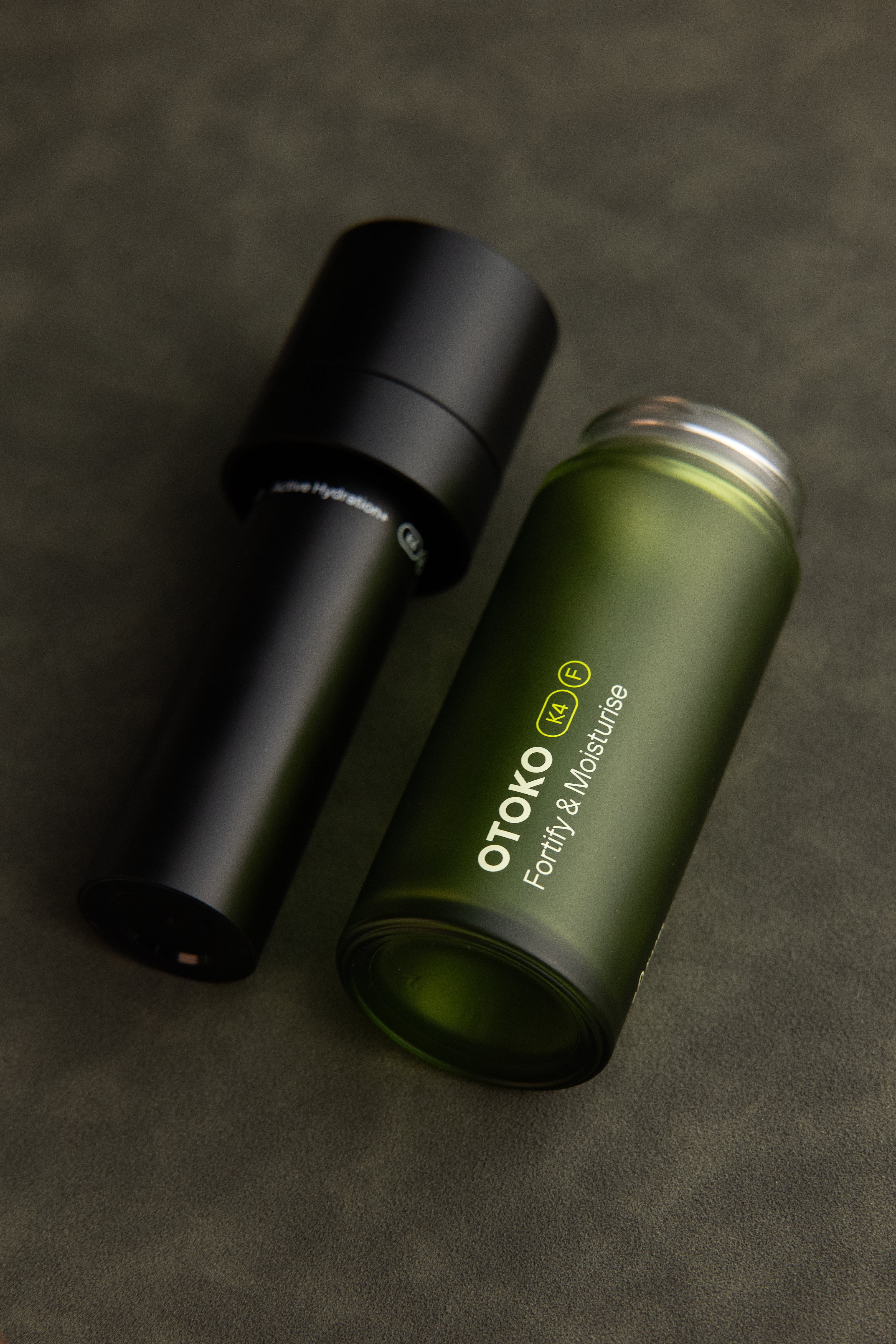 Two skincare products on a dark surface, one black and one green.